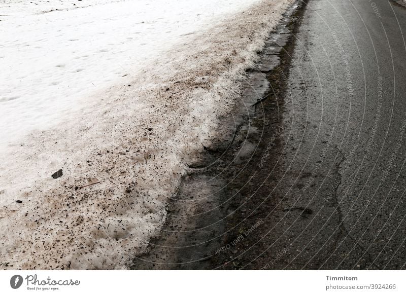 Schnee und Dreck neben Straße im Schwarzwald Asphalt schwarz weiß feucht glänzend schmutzig dreckig Menschenleer Verkehrswege