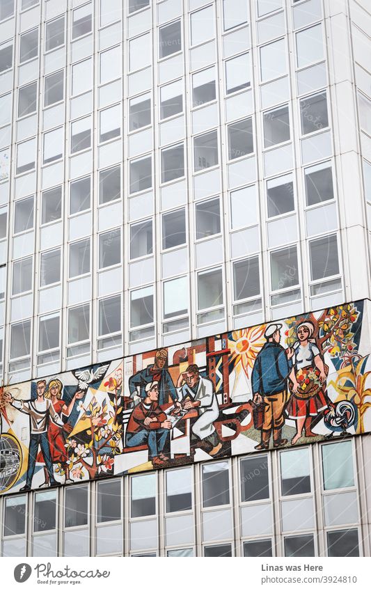 Einmal in Berlin, Deutschland. Die Stadt ist voll von großartiger Architektur und dieses Stück zeigt ein Gebäude mit einer Vintage-Freske voller Arbeiterhelden. Ein stimmungsvolles und graues Gebäude wird mit diesem kleinen Akzent wieder zum Leben erweckt.