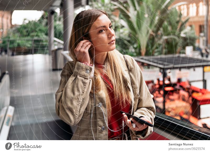 Junges Mädchen mit Kopfhörer Porträt jung 20s Vorderansicht blond hübsch Telefon per Telefon Funktelefon Kaukasier Blick Stehen Frau Smartphone hören benutzend