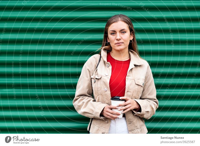 Hübsches junges Mädchen Porträt in die Kamera schauen Tasse Kaffee grüner Hintergrund Stehen hübsch Frau außerhalb im Freien Vorderansicht posierend eine Person