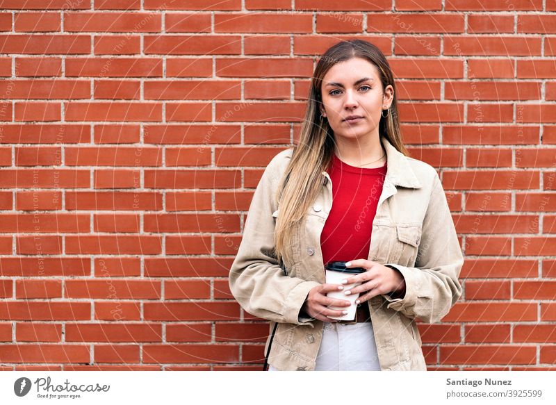 Junges Mädchen Porträt in die Kamera schauen Tasse Kaffee Wand Stehen hübsch Frau jung außerhalb im Freien Vorderansicht posierend eine Person allein