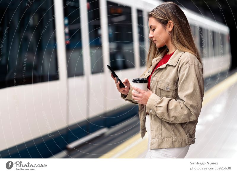 Blondes Mädchen wartet auf den Zug Seitenansicht Frau Kaukasier Bewegung Porträt per Telefon Tippen Blick Hintergrund Stehen im Innenbereich U-Bahn Verkehr
