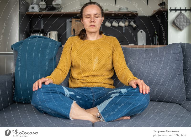 Frau übt Yoga zu Hause meditierend Erholung Sitzen Wohlbefinden Wellness Gleichgewicht heimwärts Lifestyle Person Erwachsener im Schneidersitz trainiert.