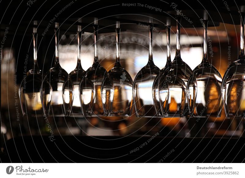 Nahaufnahme von in einem Regal hängender Weingläser in dunkler Umgebung eines Restaurants Glas Licht Reflexion Gläser strukturiert zerbrechlich Weinglas