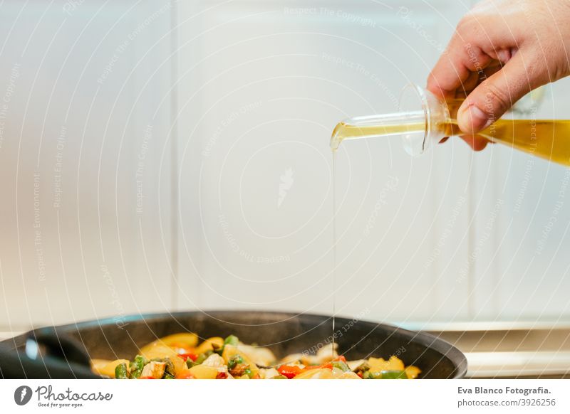 unkenntlich Mann bereitet Gemüse Essen in der Pfanne. Hinzufügen von Olivenöl. Gesundes Essen oliv Erdöl Lebensmittel Küche Paprika farbenfroh Gesundheit Möhre