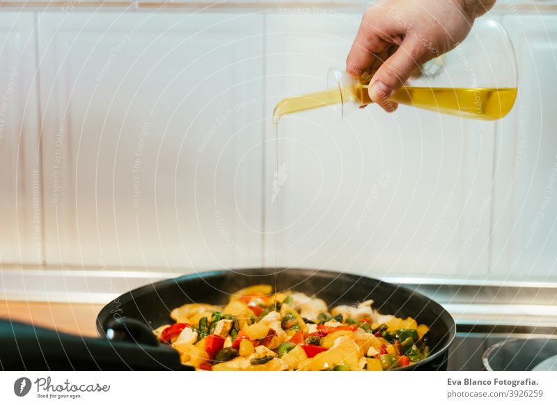 unkenntlich Mann bereitet Gemüse Essen in der Pfanne. Hinzufügen von Olivenöl. Gesundes Essen oliv Erdöl Lebensmittel Küche Paprika farbenfroh Gesundheit Möhre