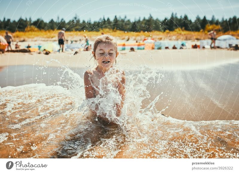 Kleines Mädchen spritzte durch Meer Welle beim Sitzen und Spielen am Strand Erholung niedlich im Freien positiv Sonnenlicht Sommerzeit platschen Familie