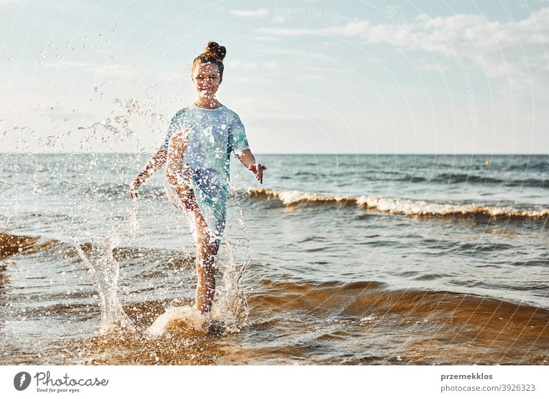 Mädchen spritzt ein Wasser in Richtung Kamera genießen eine freie Zeit über Meer an einem Strand bei Sonnenuntergang aufgeregt positiv Emotion sorgenfrei Natur