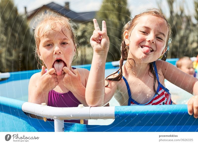 Glückliche Mädchen machen V Zeichen Geste dummes Gesicht spielen in einem Pool authentisch Hinterhof Kindheit Kinder Familie Spaß Garten Fröhlichkeit Freude