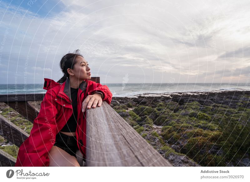Nachdenkliche Frau sitzt an der Meeresküste MEER Ufer besinnlich allein nachdenklich ruhen nachdenken träumen jung asiatisch ethnisch Meeresufer Freiheit einsam