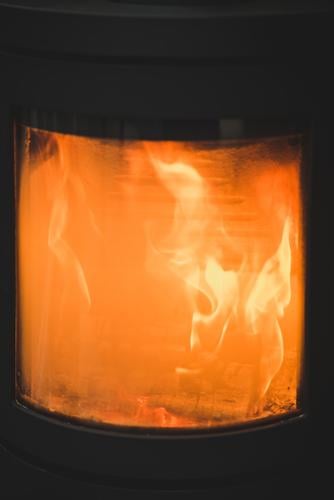 Das Feuer brennt im Ofen und heizt das Haus | Es ist warm, gemütlich und geborgen zu Hause heizen Brennstoff gehacktes Holz Vorrat brennen Heizung Wärme