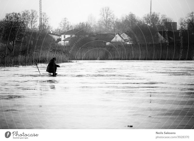 einsamer fischer auf dünnem 5 cm eis. eisfischen ist ein gefährliches hobby. traditionen in Lettland. Freizeit & Hobby fangen See Seeufer Außenaufnahme Fluss