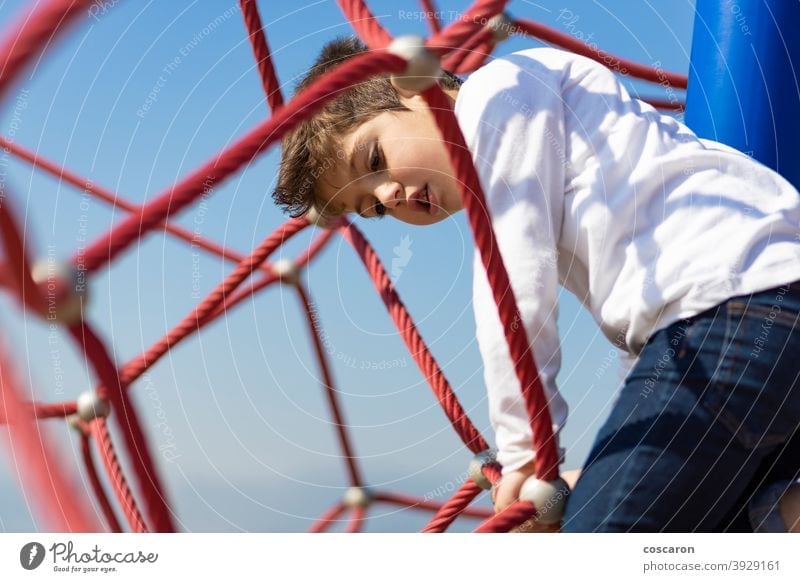 Lustiger Junge beim Klettern auf einem Spielplatz aktiv Aktivität Abenteuer Gleichgewicht Blauer Himmel Mut Kaukasier Kind Kindheit Kinder Klettergerüst Farbe