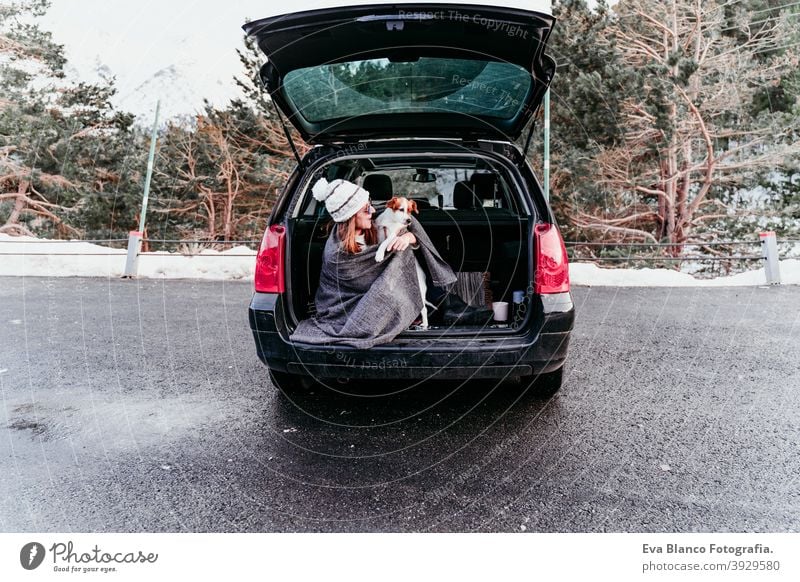 Junge Frau und niedlichen Jack Russel Hund im Auto. Wintersaison, verschneiten Berg Hintergrund Decke Natur Zusammensein Saison Fernweh Schönheit aktiv