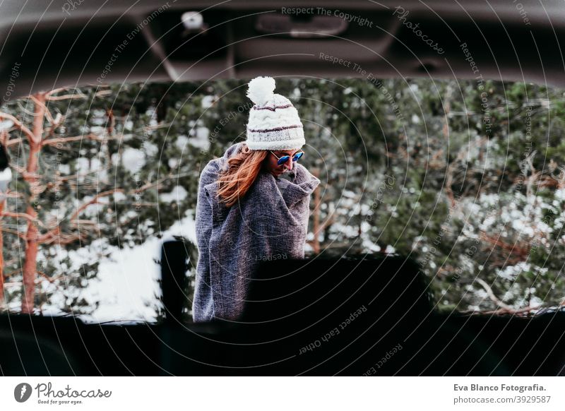 Rückenansicht aus dem Inneren eines Autos der jungen Frau im Freien trägt stilvolle Hut. Wintersaison. verschneiten Berg Hintergrund PKW Berge u. Gebirge