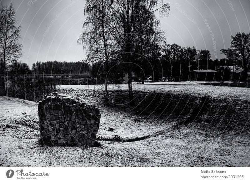 Fragment einer Ziegelmauer im Park. Landschaft mit Birken, Teich und skulpturalem Element. verschneiter Wintertag in Lettland. Spielfigur Schnee Bäume Baustein
