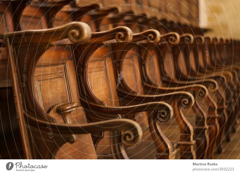 Leere Reihen von Holzstühlen im alten Kloster, Schloss. Geschwungene feine Holzdetails. Stuhl Sitz leer Aula Gericht Veranstaltung unbesetzt braun Licht