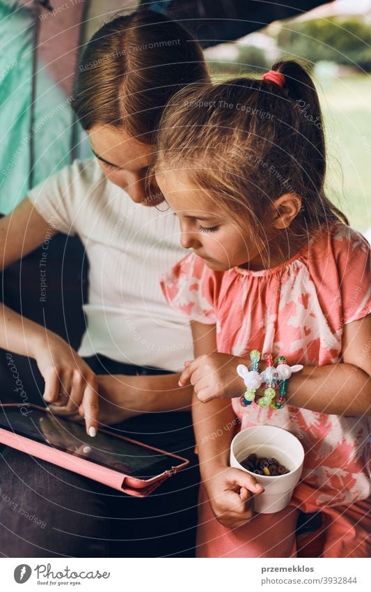 Schwestern verbringen Zeit in einem Zelt auf dem Campingplatz. Kinder mit Tablet spielen Spiele online während der Sommerferien Spielen Mädchen Geschwister