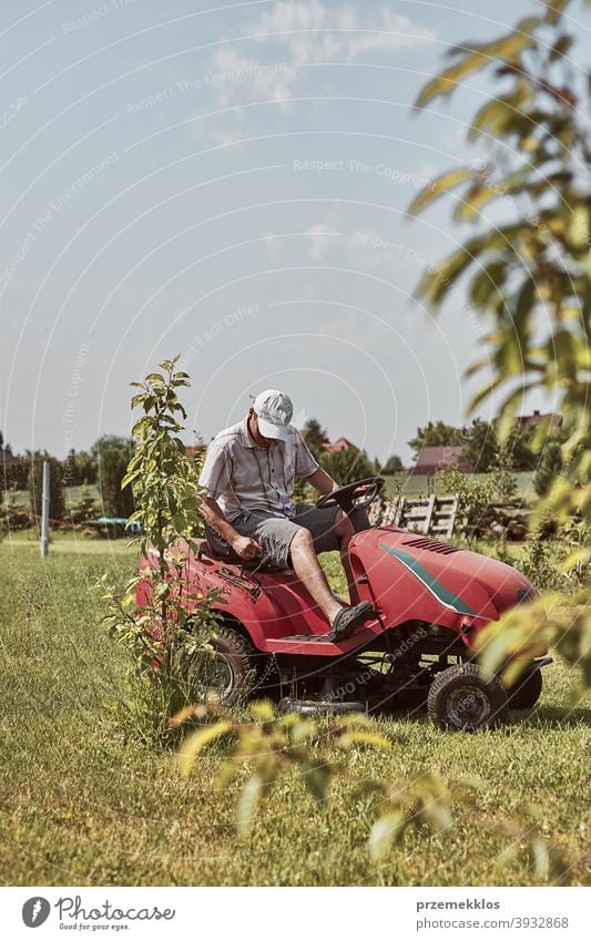 Mann mäht seinen Rasen mit einem Aufsitzrasenmäher Beruf Rasenmäher saisonbedingt geschnitten Trimmen Job Person entgittern Feld professionell