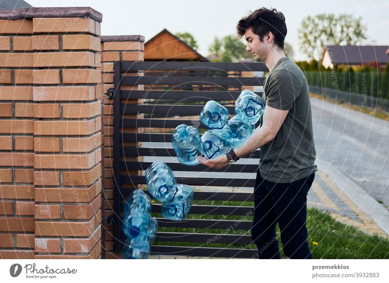 Junger Mann wirft leere gebrauchte Plastik-Wasserflaschen in den Mülleimer Behälter blau Flasche abholen sammelnd Container zerdrückt Entsorgung Ökologie Umwelt