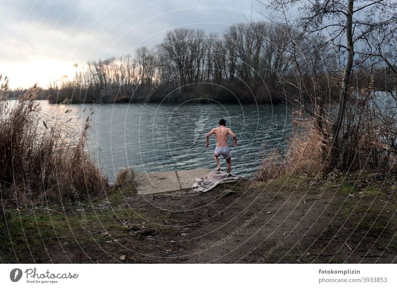 junger Mann springt im Winter zum Schwimmen in den See Eisschwimmen Junger Mann männlich maskulin Rückansicht Sportlichkeit sportlich 18-30 Jahre
