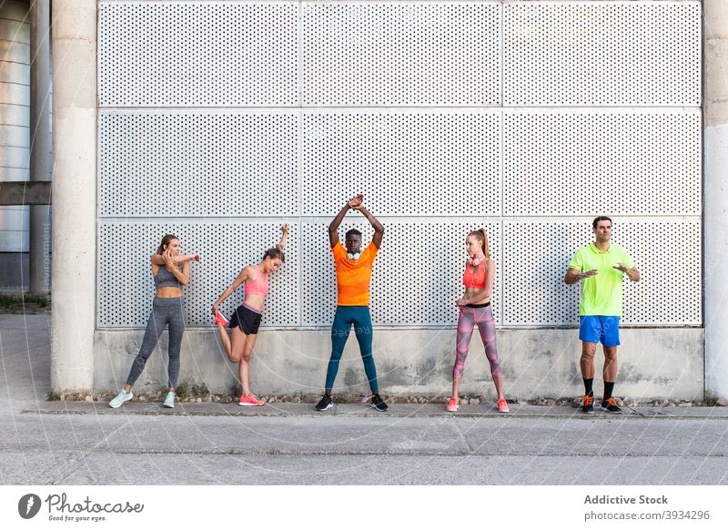 Unterschiedliche Sportler wärmen sich gemeinsam in der Stadt auf Dehnung Läufer Training Aufwärmen Großstadt Straße Unternehmen Athlet vielfältig multiethnisch