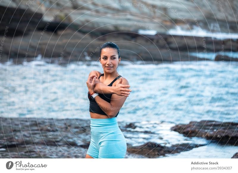 Sportlerin streckt die Arme vor dem Training Dehnung Aufwärmen Frau beweglich vorbereiten Meeresufer BH passen Übung schlank Wellness Gesundheit Wohlbefinden