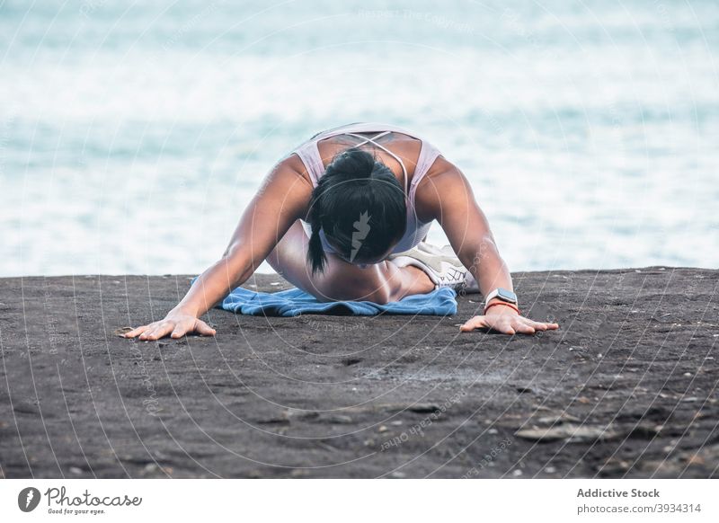 Frau macht Yoga in Sleeping Swan Pose am Strand Dehnung schlafende Schwan-Pose Asana Meeresufer beweglich Sommer sich[Akk] entspannen ruhig Windstille Ufer