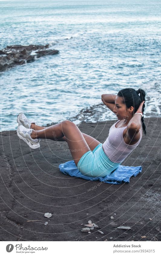 Sportliche Frau macht Bauchpressen beim Training am Meer Unterleib knirschen Bauchmuskeln Gleichgewicht Übung üben anstrengen Strand MEER Vitalität Gesundheit