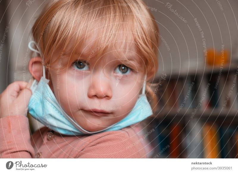 Kind mit Gesichtsmaske unter dem Kinn Mundschutz Frau Mädchen im Innenbereich heimwärts zu Hause Kaukasier schützend 2020 Sperrung Quarantäne reales Leben