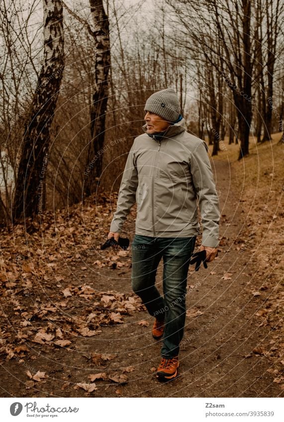 Sportlicher Rentner in der Natur beim spazieren gehen im Freien sportlich rentner Ändern Mann Porträt mütze Winter Kälte Landschaft Wald sträucher freizeit