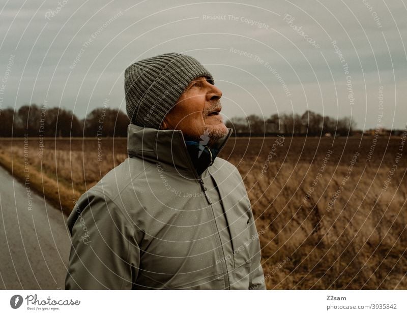 Sportliche Rentner mit Blick nach oben in der Natur spazieren im Freien sportlich rentner Ändern Mann Porträt mütze Winter Kälte Landschaft Wald sträucher