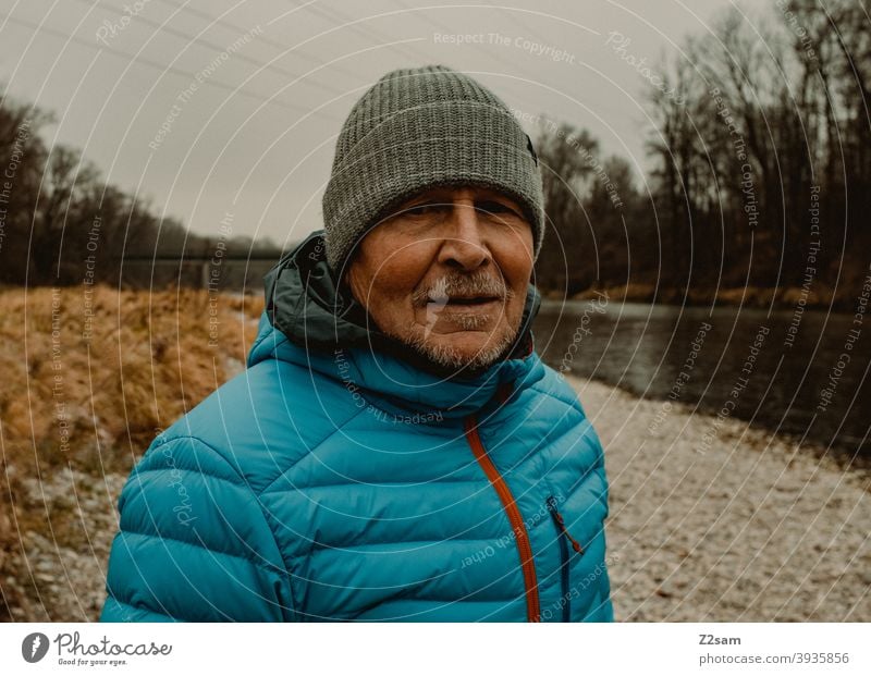 Portrait eines sportlichen Rentners in der Natur spazieren im Freien Sport rentner Ändern Mann Porträt mütze Winter Kälte Landschaft Wald sträucher Isar