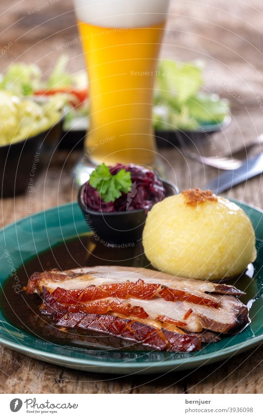 bayerischer Schweinebraten mit Knödeln rustikal Fett Dampf Schweinefleisch Braten Fleisch Teller Deutschland weiß Mittagessen Kloß Kartoffel Gericht geröstet