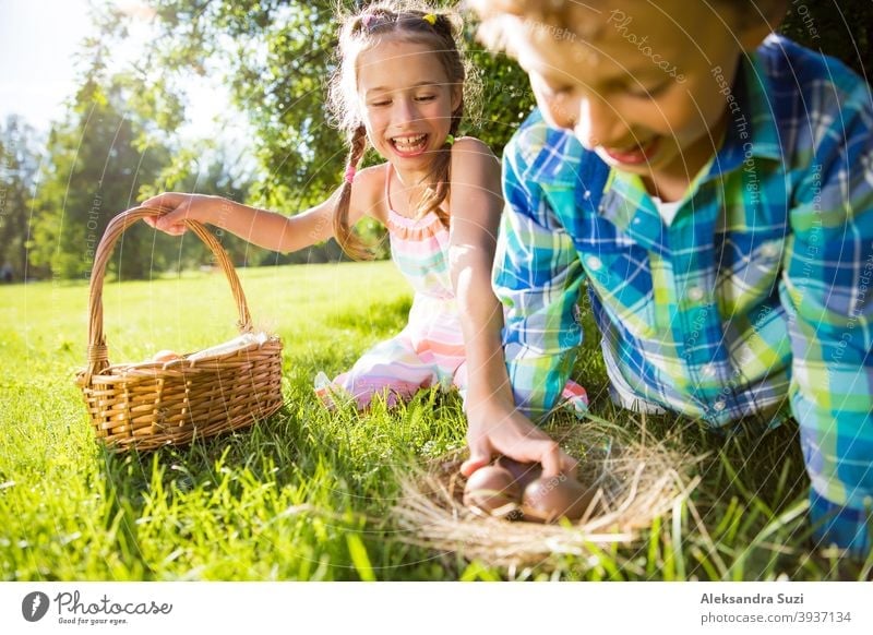 Netter Junge und Mädchen feiern Ostern, suchen und essen Schokoladeneier. Glückliche Familie Urlaub. Glückliche Kinder lachen, lächeln und Spaß haben. Schöner Frühling sonnigen Tag im Park