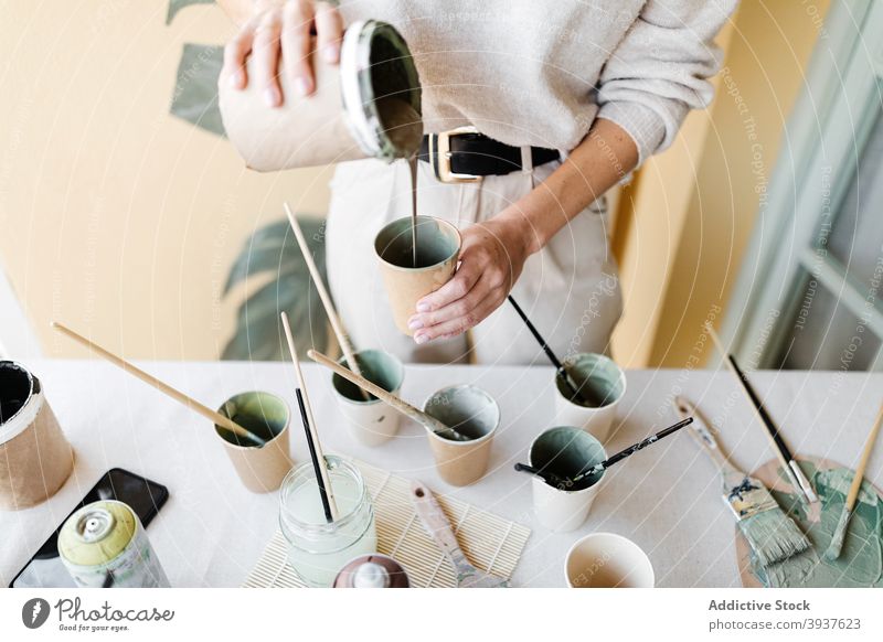 Frau mischen Farben für die Erstellung von Gemälde an der Wand Künstler Anstreicher heimwärts Pigment eingießen Fensterblätter Blatt Mundschutz behüten Tasse