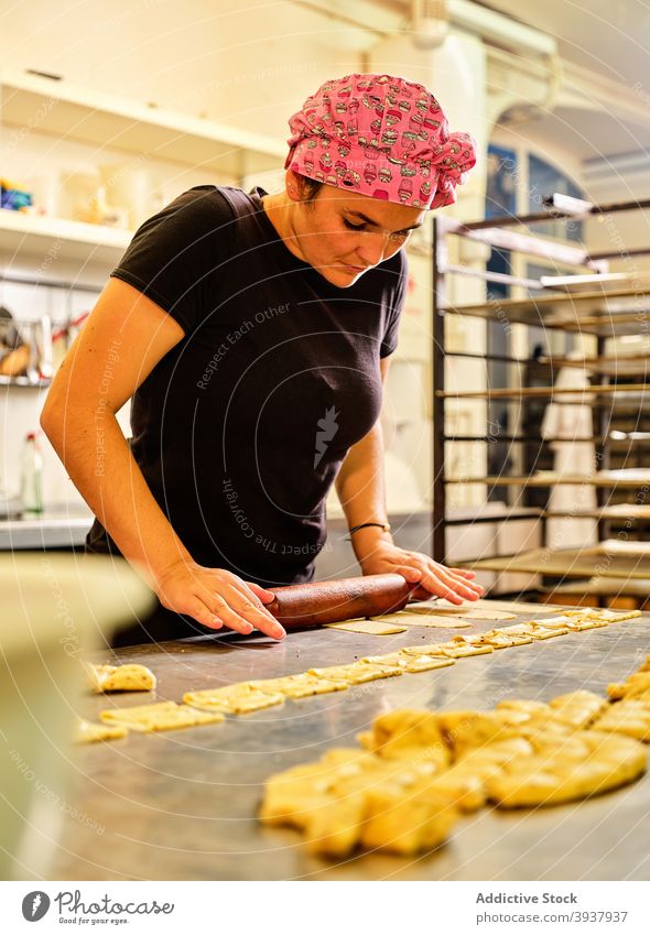 Koch bei der Zubereitung von Gebäck in einer professionellen Küche Teigwaren rollen Nudelholz Küchenchef vorbereiten kulinarisch Frau Lebensmittel Arbeit
