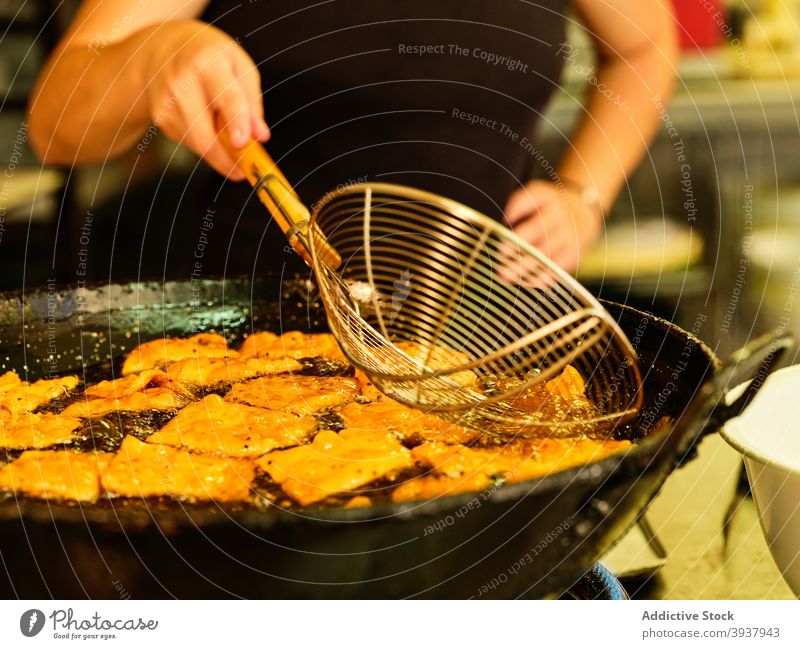 Koch bei der Zubereitung von frittiertem Gebäck Teigwaren tief braten Küchenchef vorbereiten Erdöl kulinarisch Lebensmittel professionell Arbeit Prozess Job