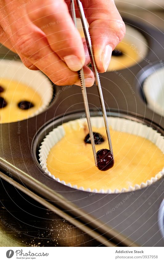 Konditorin macht Muffins mit Beeren Gebäck Bäckerei Konditorei Teigwaren hinzufügen vorbereiten Küchenchef professionell kulinarisch tong süß Dessert Koch