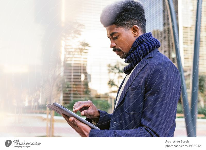 Schwarzer männlicher Unternehmer mit Tablet in der Stadt freiberuflich Mann Browsen Tablette Arbeit Projekt abgelegen Großstadt Business ethnisch schwarz