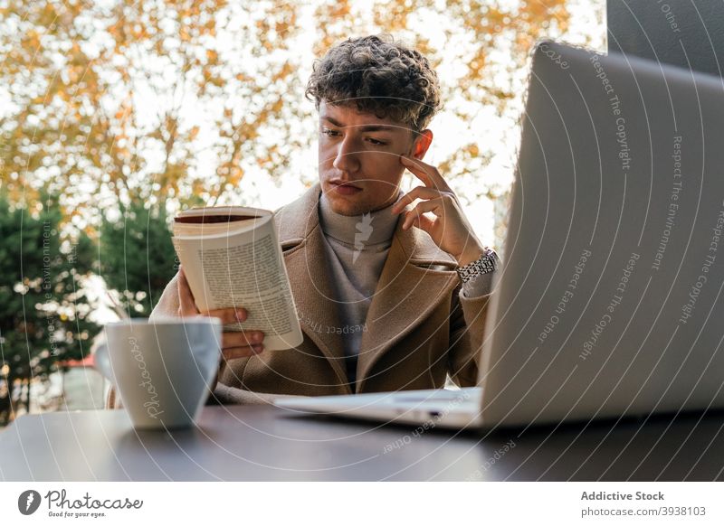 Konzentrierter Mann beim Lesen eines Buches im Café lesen ernst nachdenklich Großstadt besinnlich Roman Literatur männlich Tisch Outfit interessant Etage jung