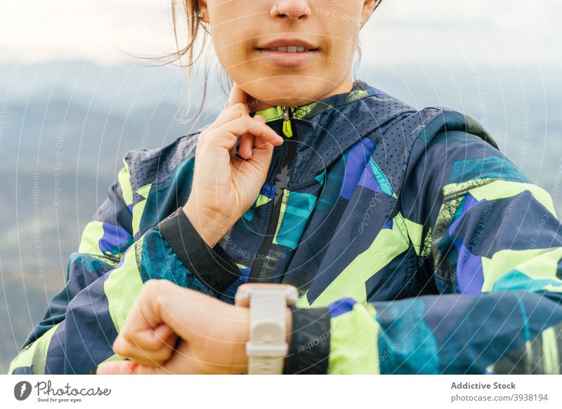 Sportliche junge ethnische Frau, die beim Wandern auf einem Berggipfel ihre Armbanduhr überprüft Sportlerin prüfen Zeit Training Berge u. Gebirge Wanderung