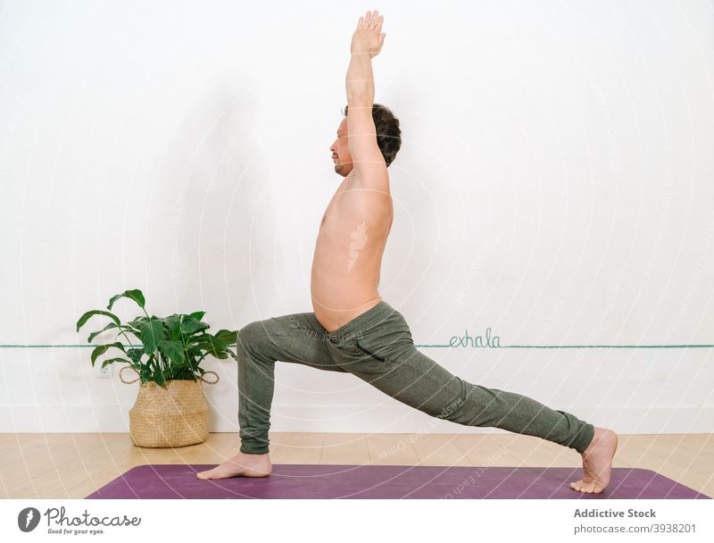 Mann stehend in Crescent Lunge Pose im Yoga-Studio üben Sichel-Lungen-Pose anjaneyasana Achtsamkeit Harmonie friedlich nackter Torso männlich Zen ruhig