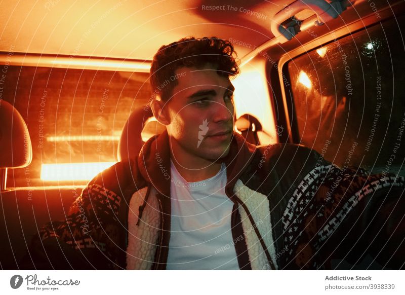 Stilvoller junger Mann sitzt im Auto mit rotem Neonlicht in der Nacht PKW selbstbewusst besinnlich neonfarbig leuchten nachdenklich Fahrer Nachtleben modern