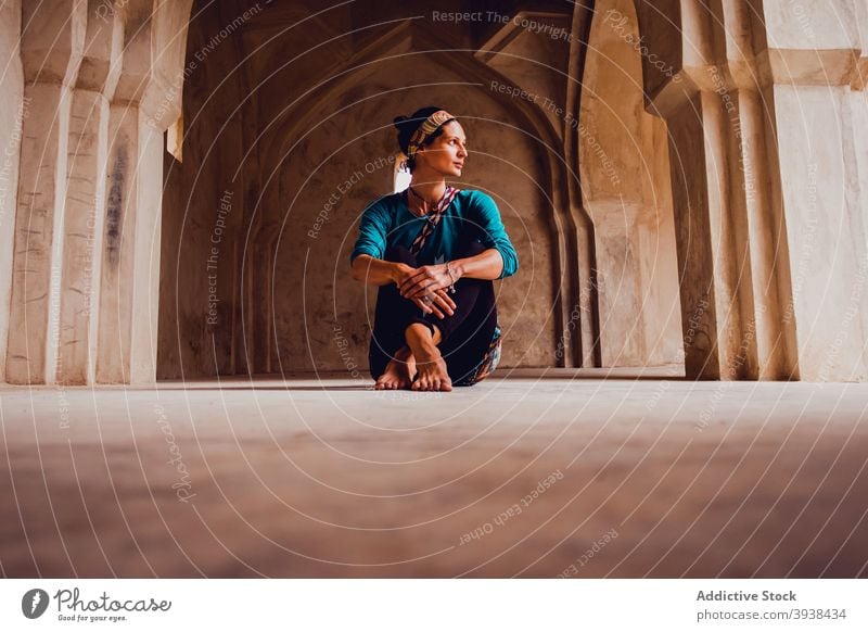 Anmutige junge ethnische Frau entspannt auf dem Boden in geräumigen orientalischen Tempel sich[Akk] entspannen Stock Palast Orientalisch Architektur friedlich