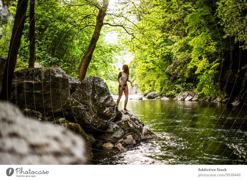 Wunderschöne junge gebräunte Dame in Badebekleidung entspannen auf felsigen Klippe in der Nähe von See im Wald Frau sich[Akk] entspannen Regenwald Reisender