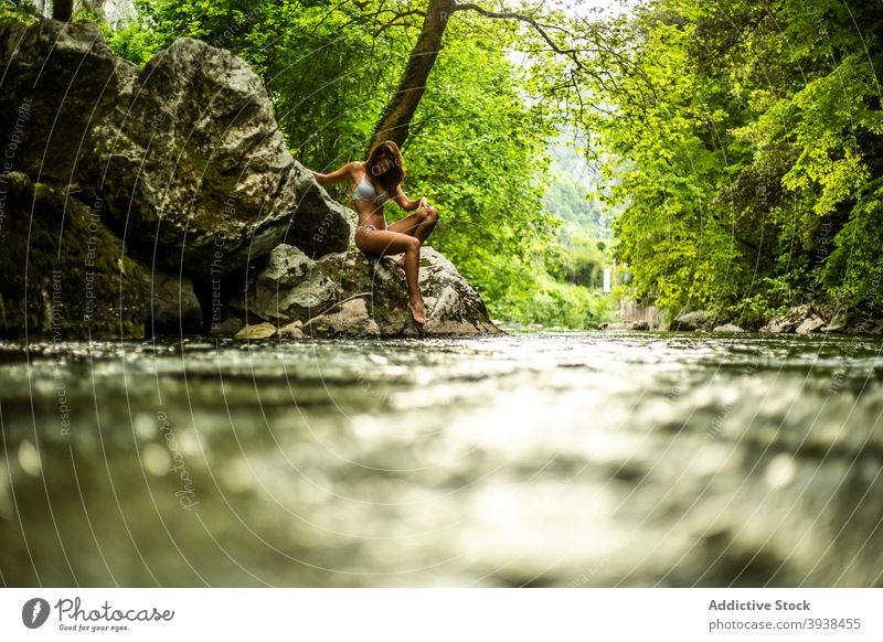 Wunderschöne junge gebräunte Dame in Badebekleidung entspannen auf felsigen Klippe in der Nähe von See im Wald Frau sich[Akk] entspannen Regenwald Reisender