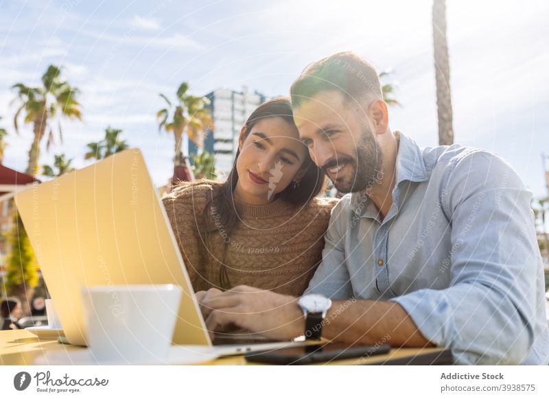 Fröhlich junges Paar teilen Laptop und lachen in Straßencafé zuschauen Video Lachen Spaß haben Café Liebe Zusammensein heiter Termin & Datum Punkt aufgeregt