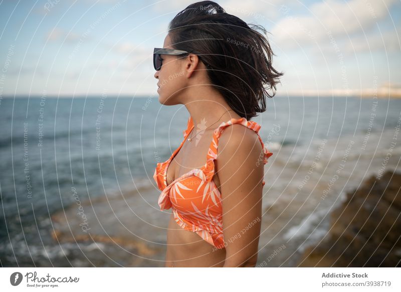 Nachdenkliche junge ethnische Frau entspannt an der Meeresküste gegen bewölkten Sonnenuntergang Himmel sich[Akk] entspannen Meeresufer Urlaub verträumt Erholung