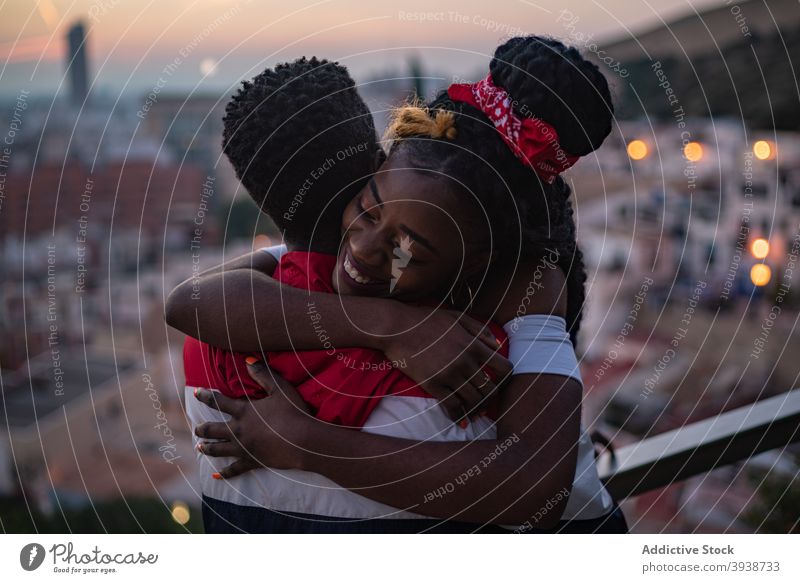 Glückliches junges afroamerikanisches Paar, das sich bei Sonnenuntergang auf dem Dach umarmt Umarmen Dachterrasse Liebe Partnerschaft Zuneigung Großstadt